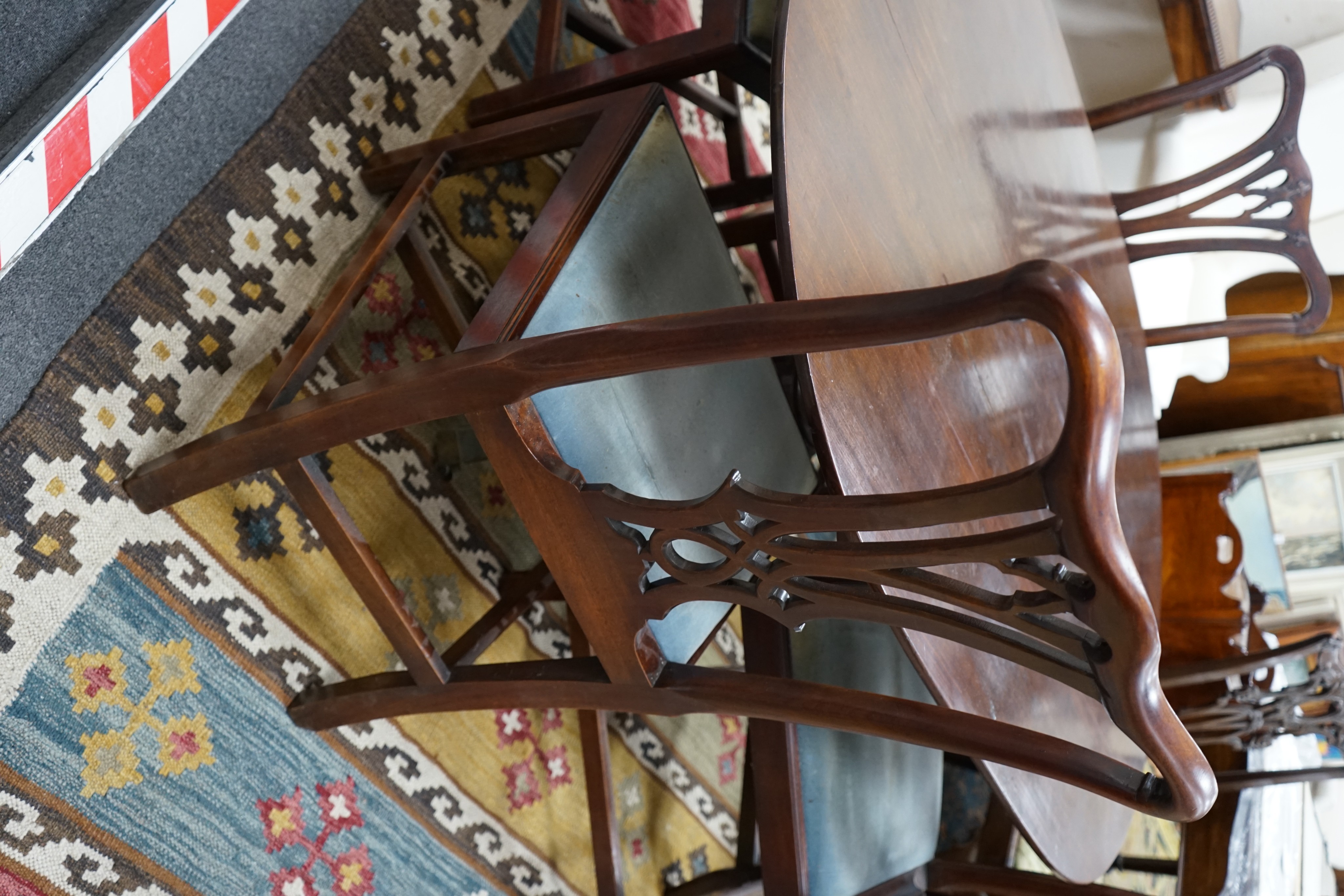 A George III oval mahogany tilt top dining table, altered, width 146cm, depth 106cm, height 69cm together with four George III mahogany dining chairs